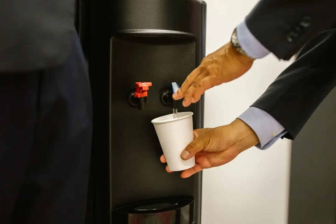 Man dispensing water from an office water cooler